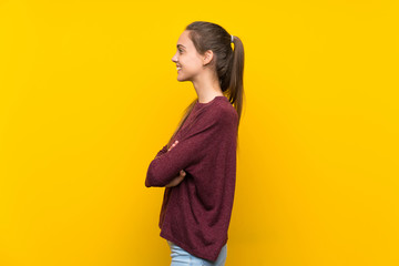 Young woman over isolated yellow background in lateral position