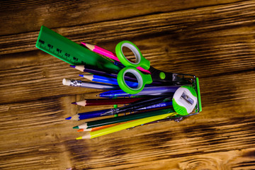 Small shopping cart with different school stationery on a wooden background. Back to school concept. Top view