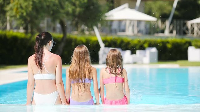 Mother and two kids enjoying summer vacation in luxury swimming pool