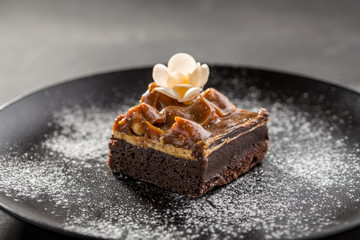 Brownies with Caramel Sauce on black plate on black background