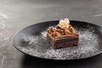 Brownies with Caramel Sauce on black plate on black background