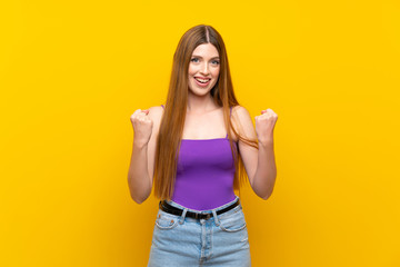 Young woman over isolated yellow background celebrating a victory in winner position