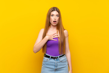 Young woman over isolated yellow background surprised and shocked while looking right