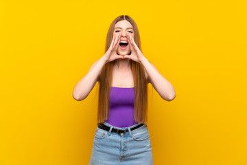 Young woman over isolated yellow background shouting and announcing something