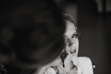 Young girl is looking at the camera while a stylist is doing a makeup on her face.