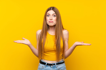 Young woman over isolated yellow background having doubts with confuse face expression