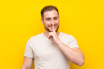 Handsome man over yellow background doing silence gesture