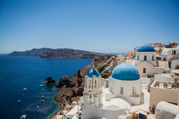 Oia town on Santorini island, Greece. View of traditional white houses and churches with blue domes...