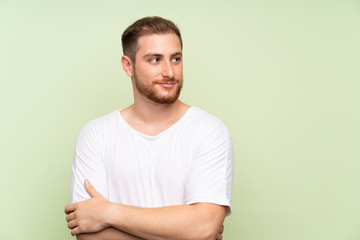 Handsome man over green background standing and looking to the side