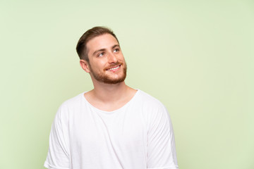 Obraz premium Handsome man over green background laughing and looking up