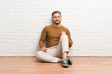Blonde man sitting on the floor standing and looking to the side