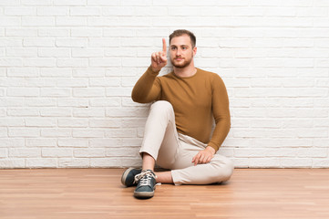 Blonde man sitting on the floor touching on transparent screen