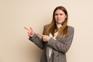 Young business woman frightened and pointing to the side