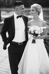 A bride and a groom are walking together. Black and white image.