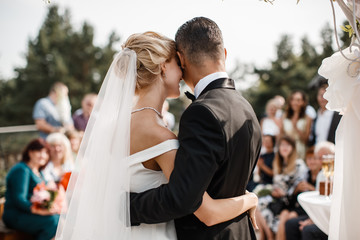 A bride and a groom are hugging in front of the guests.