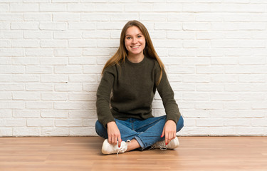 Young woman sitting on the floor keeping the arms crossed in frontal position