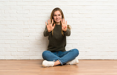 Fototapeta na wymiar Young woman sitting on the floor counting nine with fingers