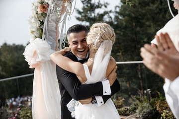 A bride and a groom are hugging, They are very happy.