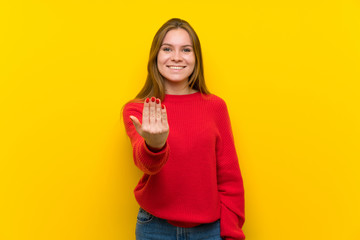 Young woman over yellow wall inviting to come with hand. Happy that you came