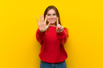 Young woman over yellow wall counting six with fingers
