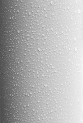 Close-up of waterdrops on a clean, bent and plastic light gray surface in black and white. High resolution full frame background.