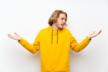 Blonde man with  sweatshirt over white wall holding copyspace with two hands