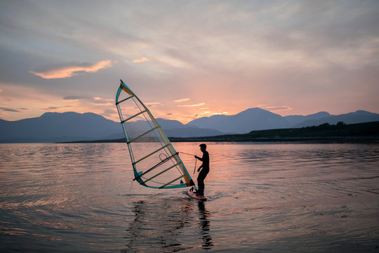 Silhouette of windsurfer on beach at sunset