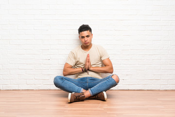 Young man sitting on the floor pleading