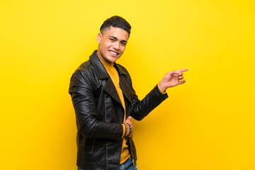 Young man over isolated yellow background pointing finger to the side