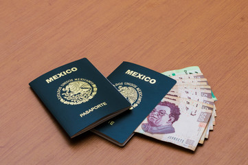 Dos pasaportes mexicanos apilados. Un paquete de billetes de quinientos pesos mexicanos dispuestos como un abanico en una mesa de madera. Pesos mexicanos en efectivo. Concepto de viajes y turismo.