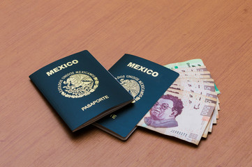 Dos pasaportes mexicanos apilados. Un paquete de billetes de quinientos pesos mexicanos dispuestos como un abanico en una mesa de madera. Pesos mexicanos en efectivo. Concepto de viajes y turismo.