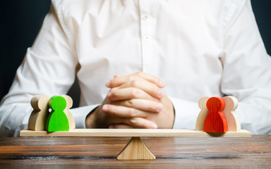 A man with hands in the gesture of a lock and looks at the red and green standoff groups on a scales. conflict resolution and the search for a compromise in the dispute. Research argument of each side