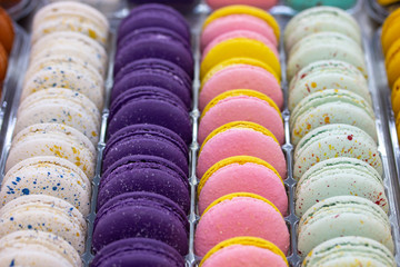French macaroons are arranged in smooth rows of white pink purple. Macaroon dough cream cakes,...