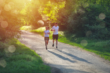 Obraz premium Young people jogging and exercising in nature, in morning sunrise warm light
