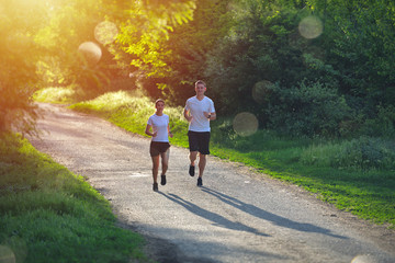 Obraz premium Young people jogging and exercising in nature, in morning sunrise warm light