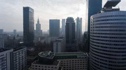 Fototapeta na wymiar Tall skyscrapers in the center of Warsaw. View from the drone. Aerial view of the financial district in the fog at dawn. Cityscape and famous skyscrapers of Warsaw.