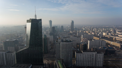 Obraz premium Downtown Warsaw skyline. Aerial view on modern skyscrapers in the fog. Modern skyscrapers are illuminated with the sure sun at sunset.