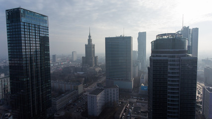 Downtown Warsaw skyline. Aerial view on modern skyscrapers in the fog. Modern skyscrapers are illuminated with the sure sun at sunset.