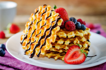 Waffeles with berries and mint leaf and a cup of tea