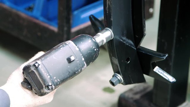 Professional mechanic working with pneumatic wrench at factory