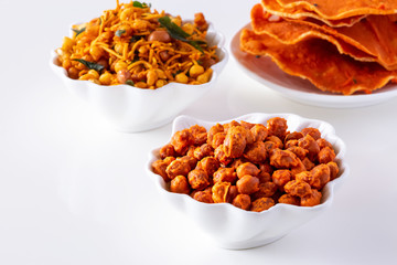 South indian spicy crunchy mix Nimco or Namkeen with peanut, rice, curry leaves and spice white bowl background isolated.