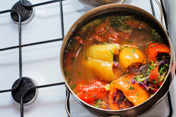 cooking  vegetarian stuffed sweet pepper with tomato in saucepan at cooker