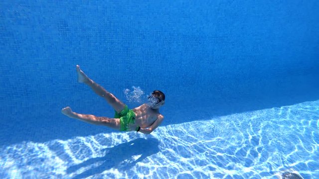 boy on summer vacation bathes dives in the pool underwater with a mask