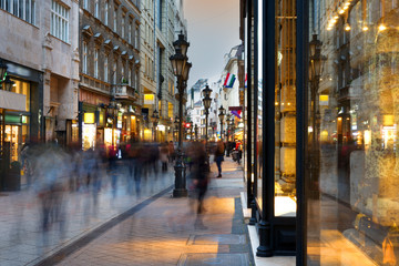 Fototapeta na wymiar Shopping street with blurred people at night