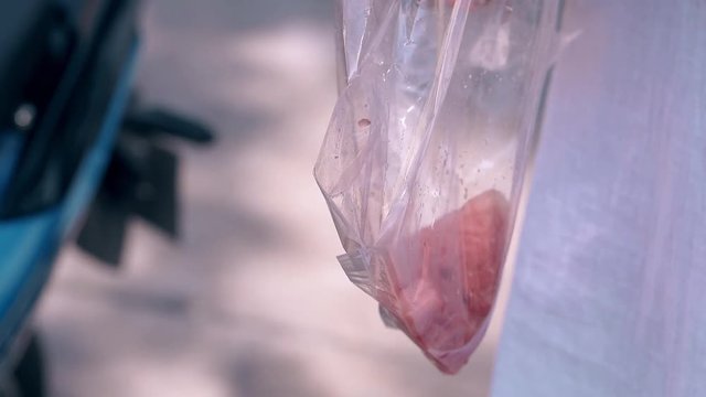 lady hand with long orange manicure impales watermelon slice on wooden stick in plastic bag close view