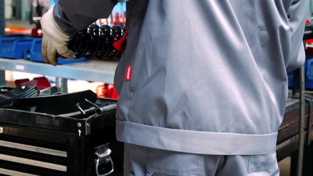 Worker inserting large spring shock absorber into machine for processing