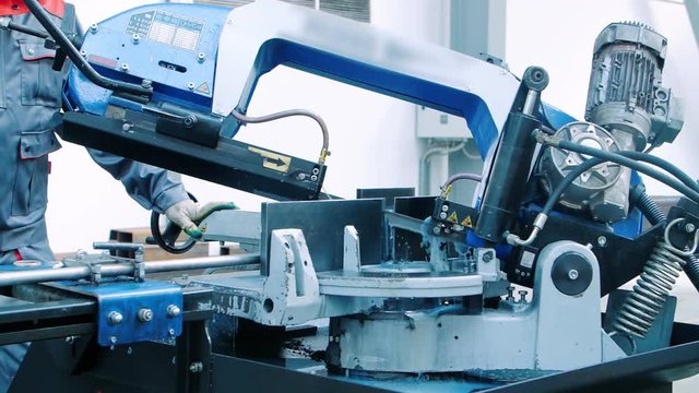 Worker operating hack saw cutting machine. Industrial machine operator