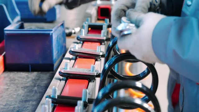 Factory worker putting metal pads on bolt. Manual work in assembly shop of plant
