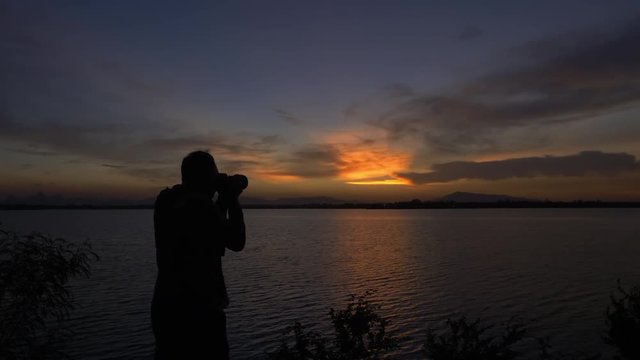 Male photographer, taking pictures of natural background twilight sky after the sunset.