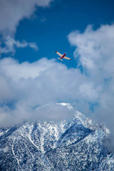 Fototapeta na wymiar Single engine plane flying over snow capped mountain tops.